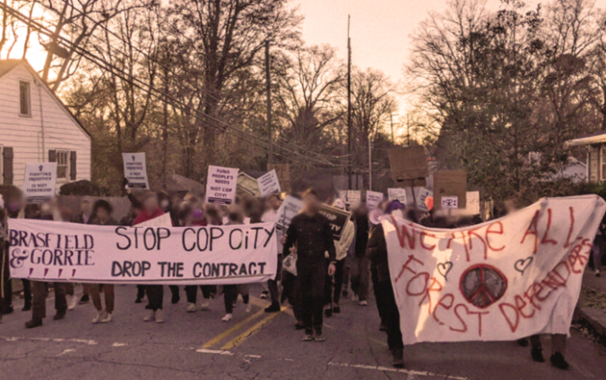 Image of a protest with people (whose faces are blurred) holding banners saying Stop Cop City and We Are All Forest Defenders.